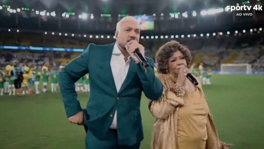 Belo e Alcione se atrapalham durante execução do Hino Nacional
